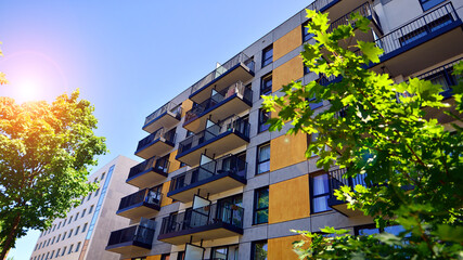 A modern residential building in the vicinity of trees. Ecology and green living in city, urban environment concept. Modern apartment building and green trees. Ecological housing architecture. 