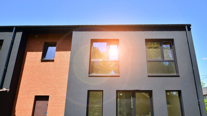 New single family houses in a new development area. Residential homes with modern facade. Terraced family homes in newly developed housing estate. The real estate market in the suburbs.