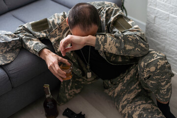 Serious anxious and nervous military man suffers from depression while sitting alone at home....