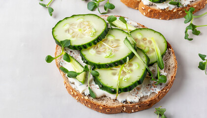 Breakfast, cereal bread sandwiches, cream cheese, sliced cucumber, with micro greenery on a light table, close-up, top view, selective focus, no people,