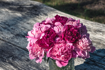 bouquet of pink peonies in glass vase on a wooden table
