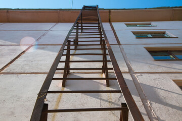 Iron ladder on the wall of the house, for emergency and fire-fighting purposes, going to the roof of the building.