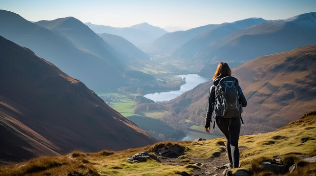 Female hiker descending a rocky path towards Sail from Crag Hill with distant views of High Stile and Red Pike