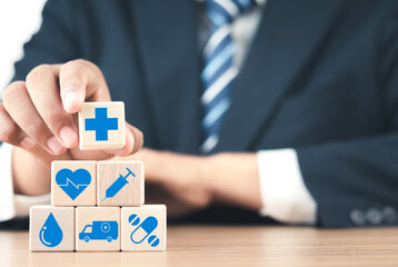 Healthcare and Insurance Concept. Businessman Stacking Wood Blocks with Medical Icons for Health Management and Future Investment. Medical Concept and Patient Care.