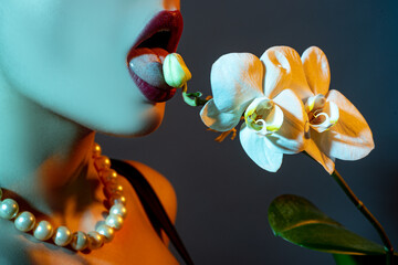 Orchid and woman lips. Orchid flower on sensual woman mouth. Sexy seductive gesture. © Volodymyr