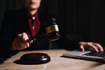 Justice and law concept.Male judge in a courtroom with the gavel, working with, computer and docking keyboard, eyeglasses, on table in morning light