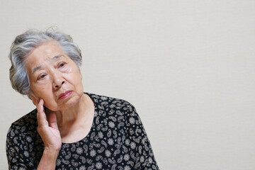 困った顔をして頬に手をやる高齢女性