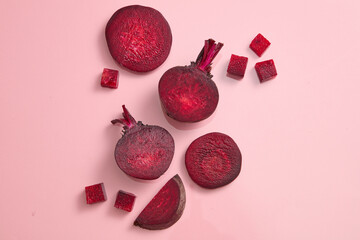 Beetroot cut in halves, slices and cubes are decorated against pink background. Beetroot (Beta...