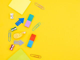 Scattered office supplies, stickers, paper clips on a yellow surface as a concept back to school and back to work in the office