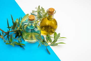 Transparent flasks with extra virgin olive oil with an olive branch on a white and blue background