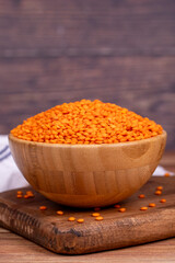 Red lentils on wood background. Raw red lentils in wooden bowl
