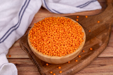 Red lentils on wood background. Raw red lentils in wooden bowl