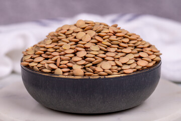 Green lentils on grey background. Raw green lentils in bowl. Close up