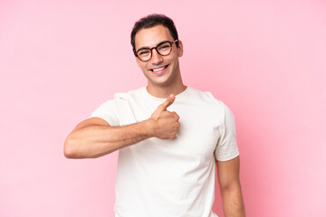 Young caucasian man isolated on pink background giving a thumbs up gesture