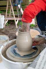 Making of mud pot on potters wheel during workshop outdoor