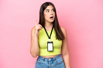 Young Brazilian woman with ID card isolated on pink background thinking an idea pointing the finger...