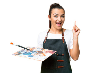 Young artist woman holding a palette over isolated chroma key background thinking an idea pointing...