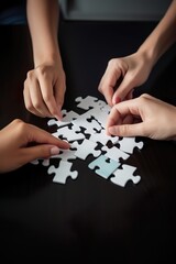 Four hands on an office table, each hand holding a puzzle piece