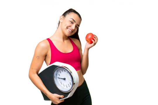 Young beauty woman over isolated chroma key background with weighing machine and with an apple