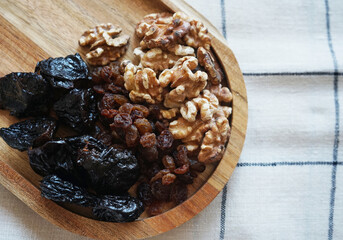 Dried fruits and nuts on a wooden plate on a checkered tablecloth