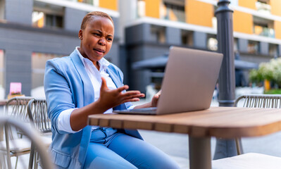 Young entrepreneur is not satisfied with the work of the company, she has a business meeting via laptop while sitting outside, casually dressed for business