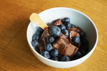 Chocolate ice cream with chocolate filling and blueberries on a wooden table