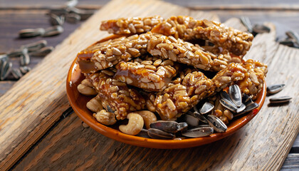 Roasted nuts and sunflower seeds in caramel and sugar on the old wooden background. Selective focus.