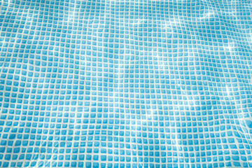 Zdjęcie przedstawia nieckę rozkładanego basenu ogrodowego wypełnionego czystą, przeźroczystą  wodą. Światło słoneczne tworzy na dnie świetlne refleksy. - 623723361