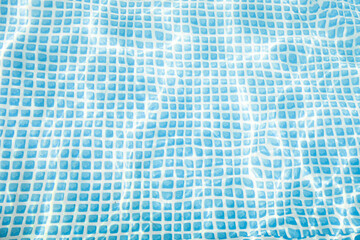 Zdjęcie przedstawia nieckę rozkładanego basenu ogrodowego wypełnionego czystą, przeźroczystą  wodą. Światło słoneczne tworzy na dnie świetlne refleksy. - 623723368