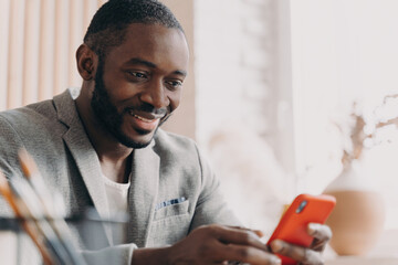 Handsome African American businessman, mobile use, chatting online, office desk, typing message,...