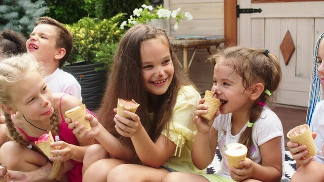 Concept of delicious food and children's happy emotions. Smiling multiethnic children eating ice cream and having fun together on family summer vacation on the summer terrace.
