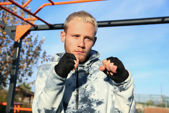 Boxer training at an outdoor gym. Young man in a boxing stance. Close up, copy space, background.