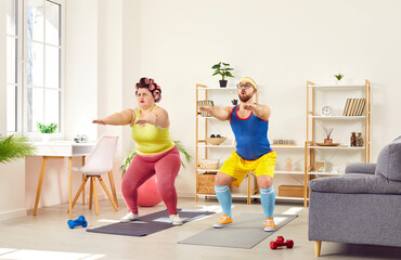 Funny family couple doing squat exercises together at home. Ridiculous plus size woman and slender...