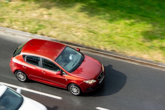 Seat Ibiza Mk4 6J or 6P model with wine red colour driving quickly on wet road overtaking a vehicle
