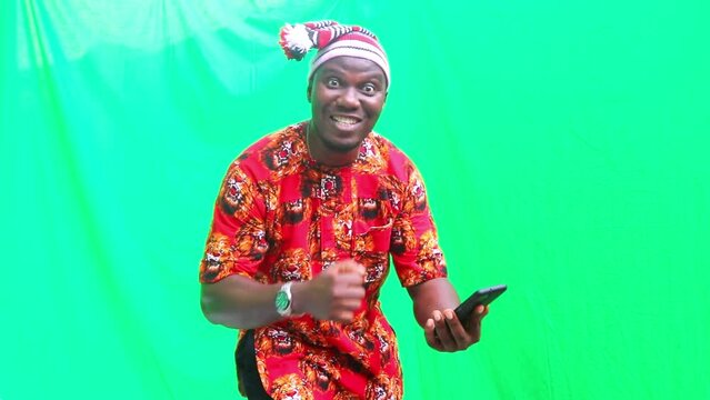 Traditional Igbo scrolls up, down and presses enter on phone in happy news and finally shows phone screen to the camera with green screen background.