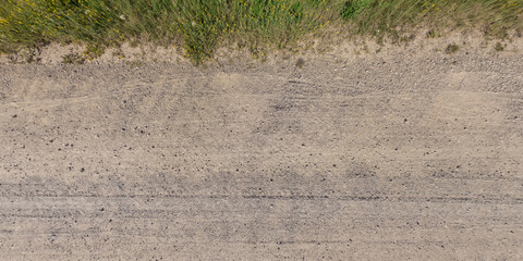 panorama of surface from above curb of gravel road with car tire tracks. © hiv360