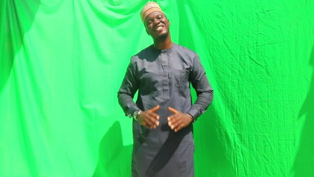Northern Nigerian of the Hausa tribe dressed business man holds hands together and bows in appreciation to the viewers