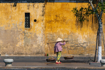 Unidentified Vietnamese merchant wearing traditional Vietnamese style conical hat "non la" at Hoi An, Vietnam.