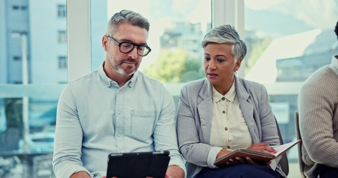 Tablet, notebook and senior business people talking in an office, planning a strategy while waiting for a meeting. Technology, collaboration or discussion with a mature man and woman in management
