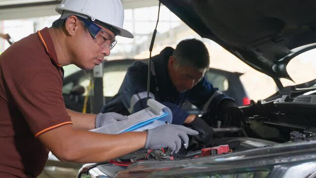 2 auto mechanics working and checking the repair work on a car at a car garage