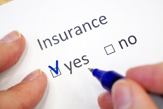 female hand fills out a questionnaire with check-box - insured yes or no? insurance checklist selection over a white background