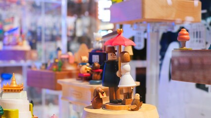 Wooden music box is spinning in a display case. Close up wooden people under an umbrella are spinning on a music box. Concept buy a music box with wooden people for a child and make him happy.