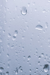 Raindrops on the window. Water falling on the glass. natural background, freshness. Cold rainy weather. Close-up.