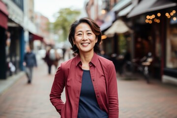 Fototapeta premium Portrait of happy mature businesswoman walking in city street. Asian woman wearing formal clothes.