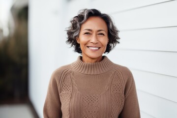 Close up portrait of smiling mature woman standing by white wall at home