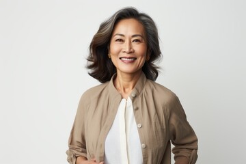 Portrait of smiling mature Asian businesswoman standing against white background.