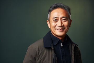 Obraz premium Portrait photography of a satisfied Indonesian man in his 50s wearing a chic cardigan against an abstract background 