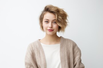 Portrait of attractive european female with blond hair, wearing beige sweater, posing over white background.