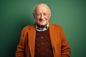Obraz premium Portrait of a senior man in a red sweater against a green background