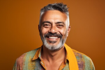 Obraz premium Portrait of a smiling middle-aged Indian man on orange background